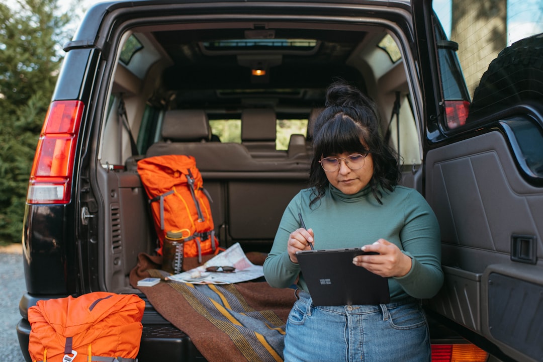 a woman standing in the back of a van holding a tablet,