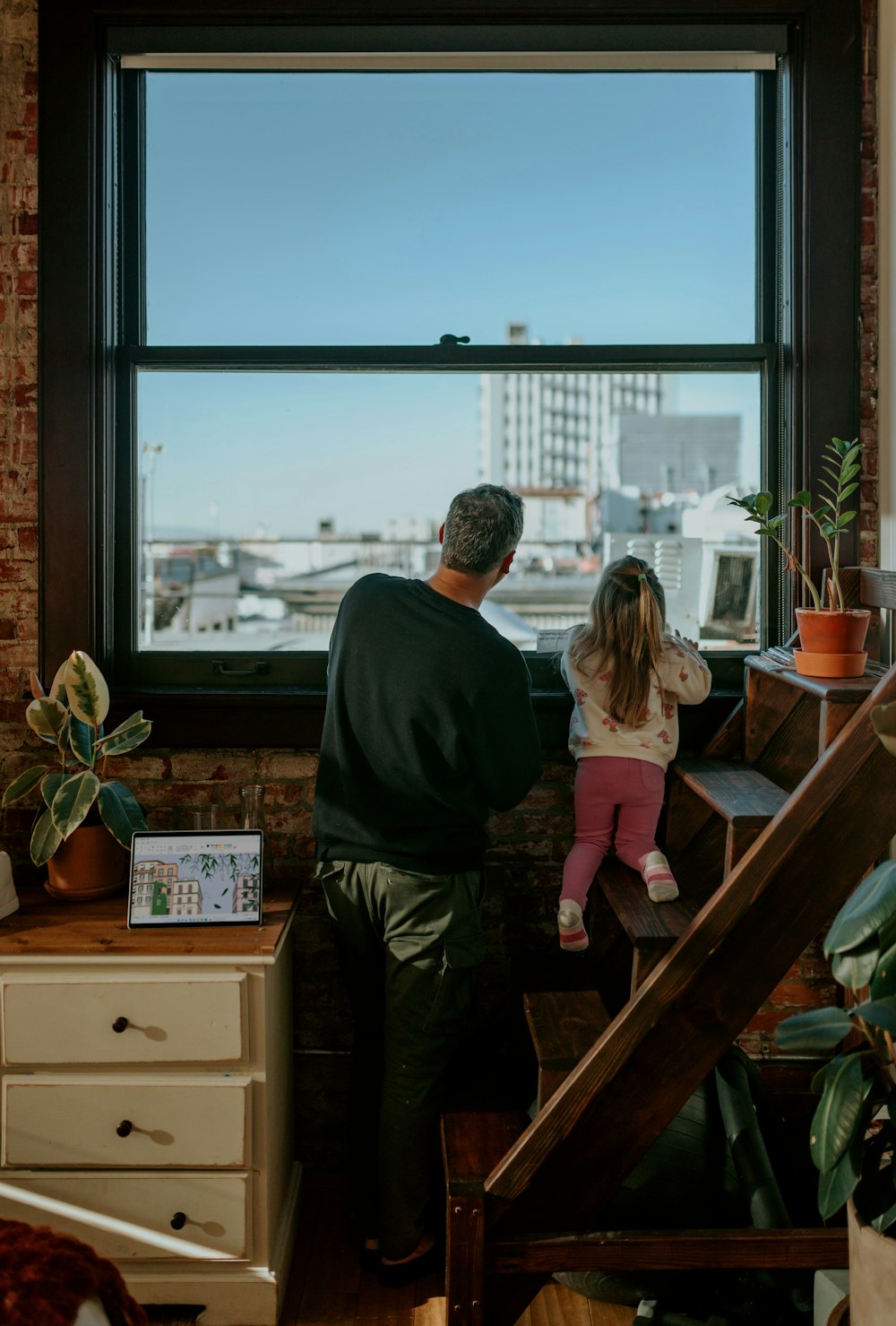 a man and a little girl are looking out a window