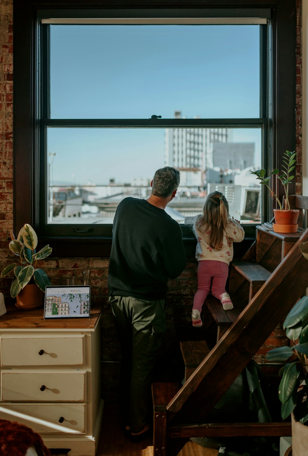 Un homme et une petite fille regardent par la fenêtre