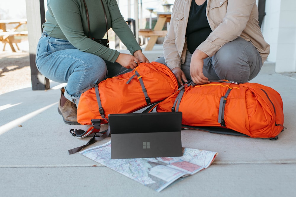 a couple of women sitting on the ground with luggage