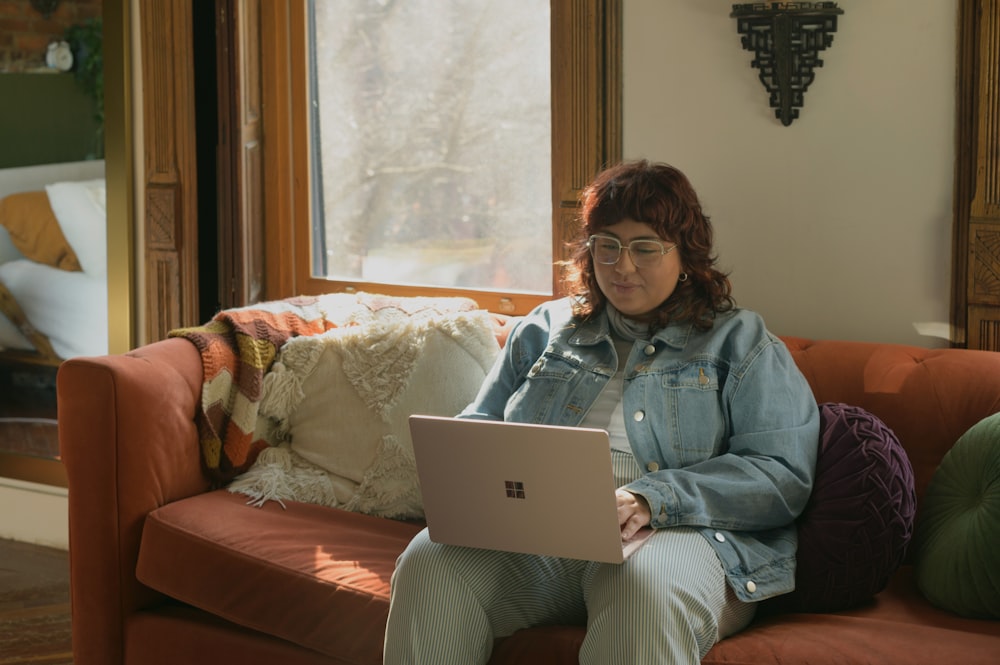 Eine Frau, die mit einem Laptop auf einer Couch sitzt