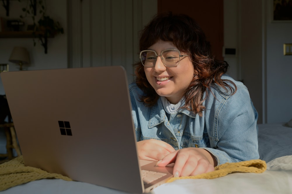 a woman in glasses is looking at a laptop