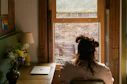 a woman sitting in a chair looking out a window