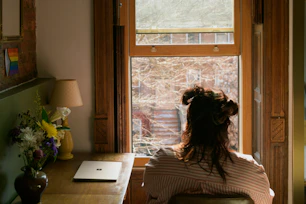 a woman sitting in a chair looking out a window