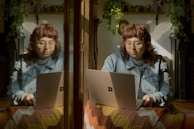 two women sitting on a bed looking at a laptop