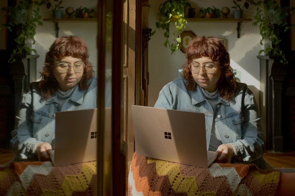 two women sitting on a bed looking at a laptop