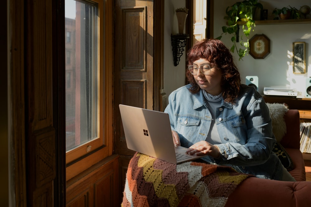 a woman sitting on a couch using a laptop computer