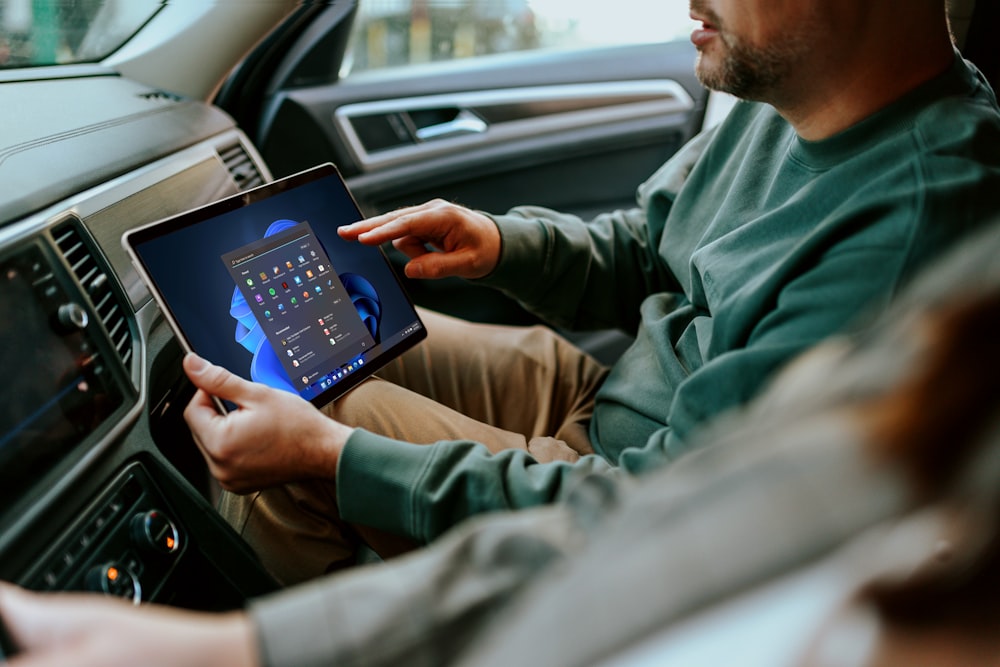 Un hombre sentado en un coche sosteniendo una tableta
