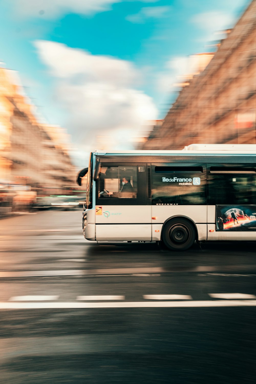 a white bus driving down a street next to tall buildings