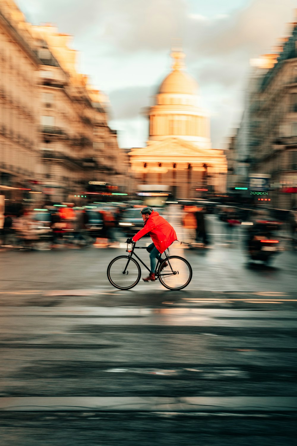 a man in a red jacket riding a bike down a street