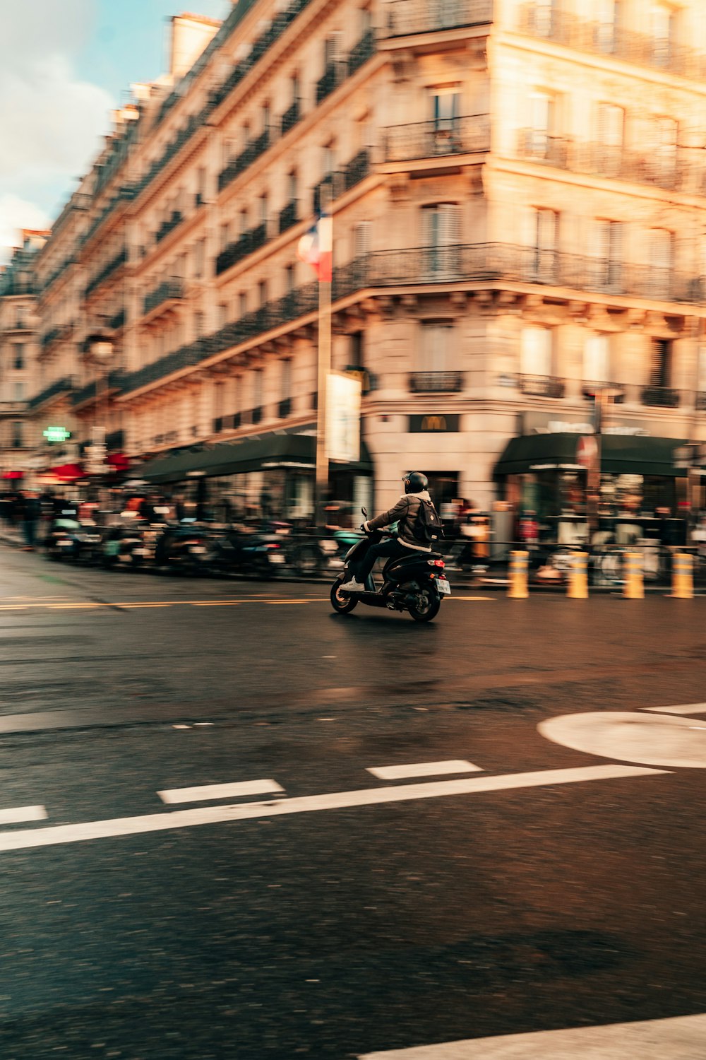 a man riding a motorcycle down a street next to tall buildings