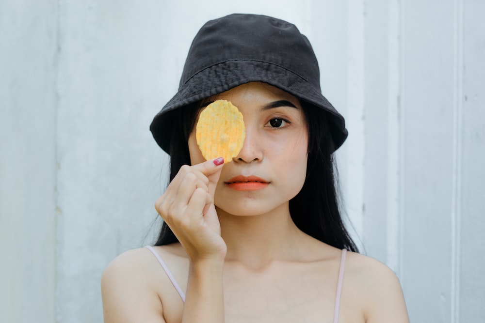 a woman with a hat holding up a piece of fruit