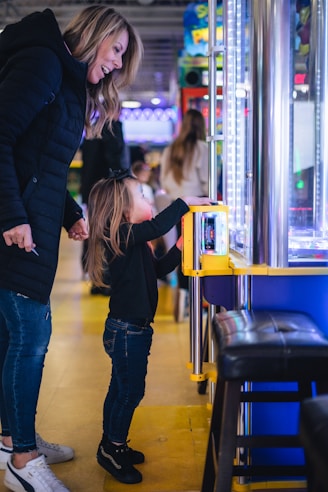 a woman and a little girl standing in front of a vending machine