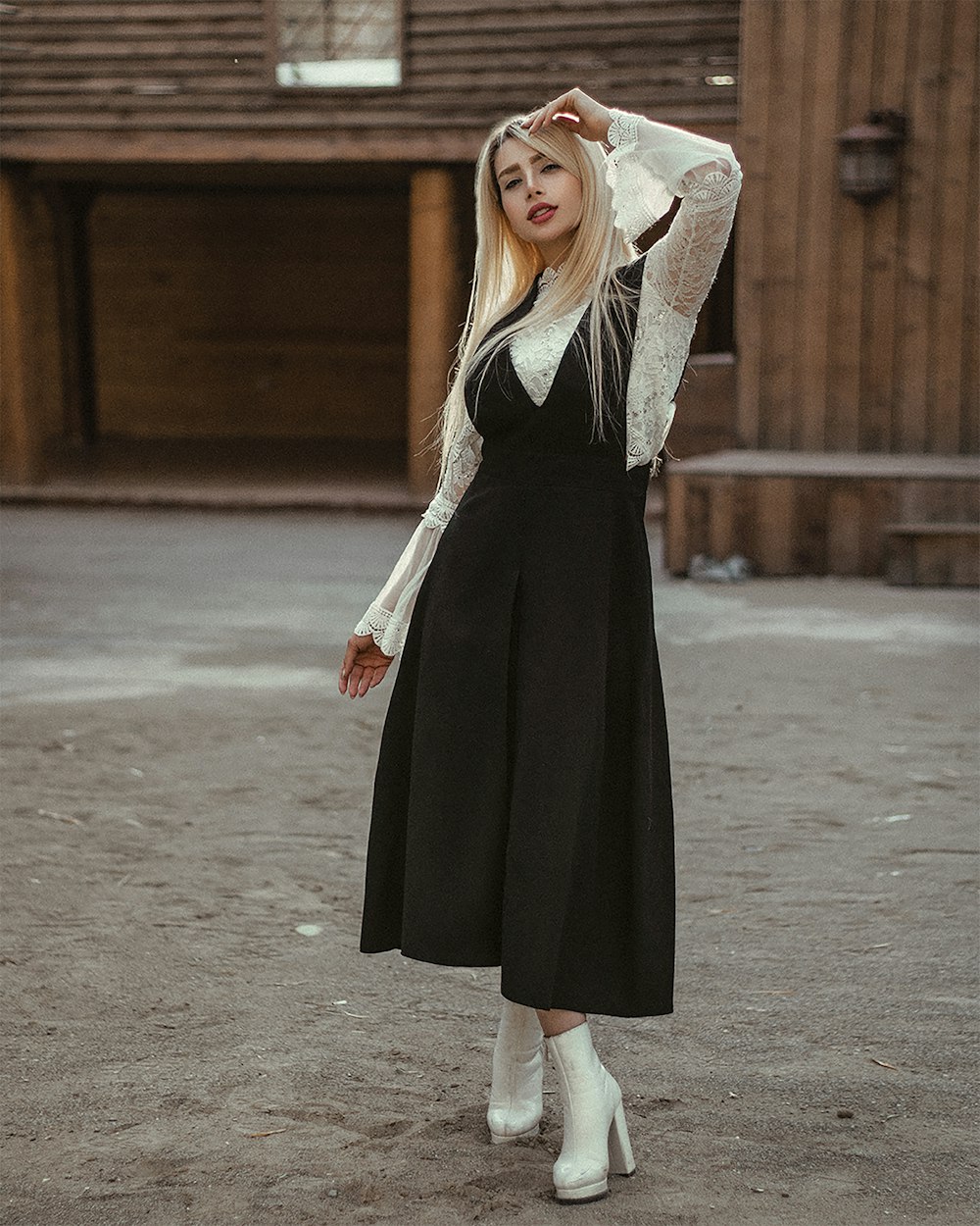 a woman wearing a black dress and white boots