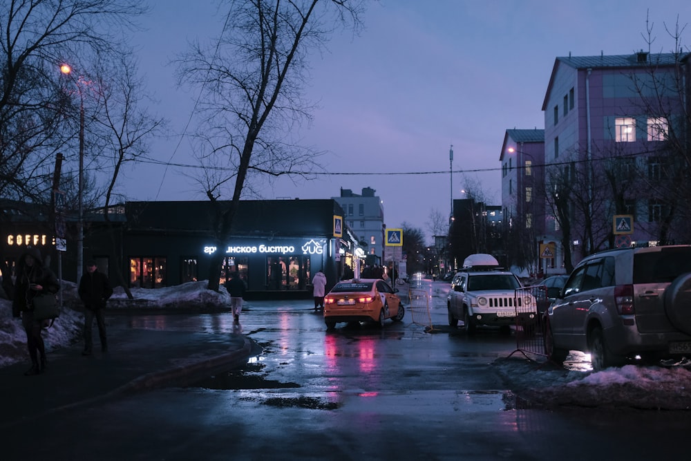 a city street at night with cars parked on the side of the road