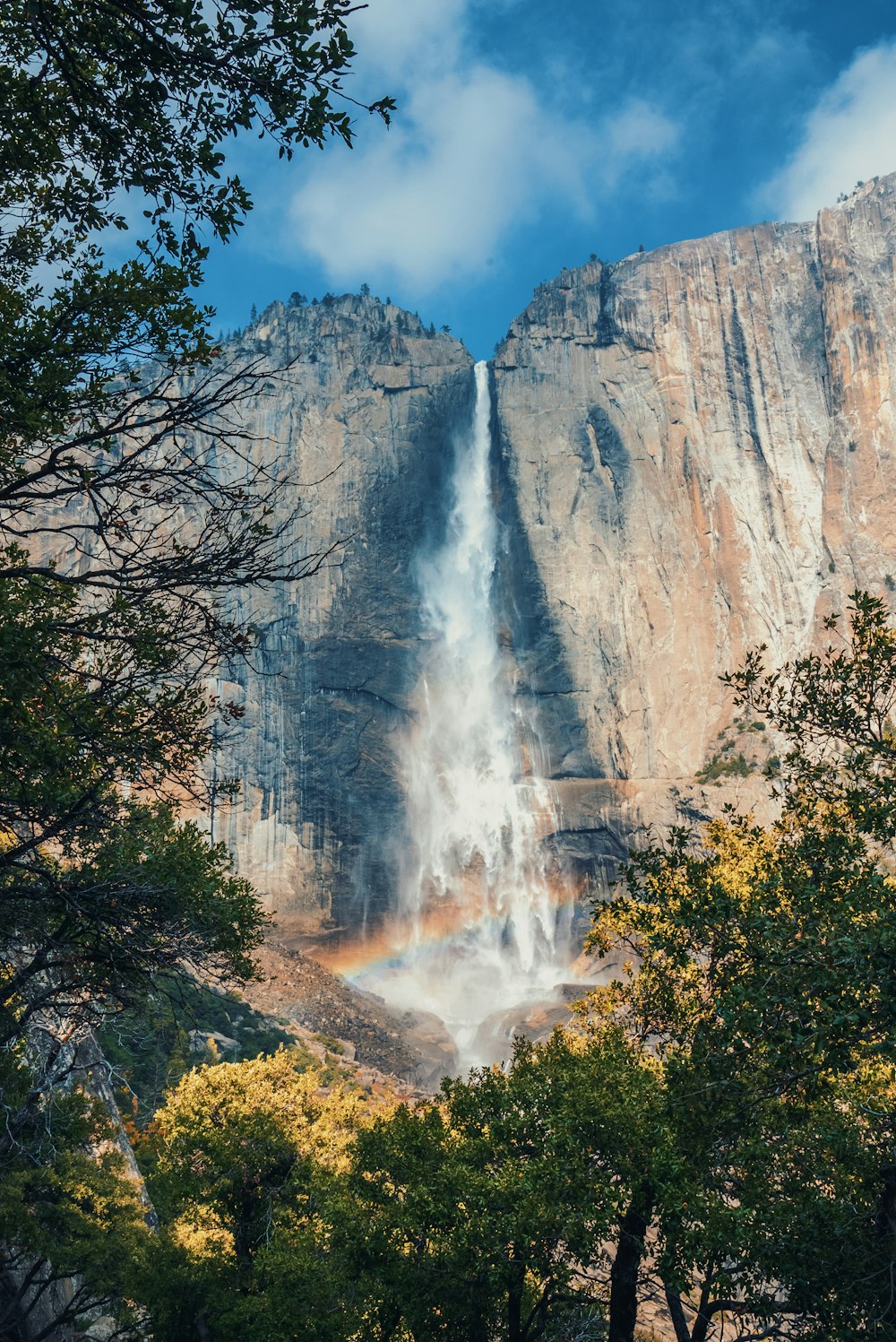 a tall waterfall with a rainbow in the middle of it