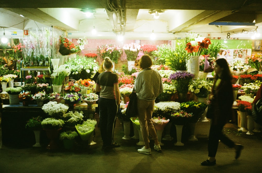 a group of people standing around a flower shop