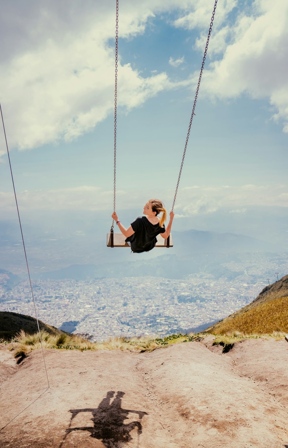 a woman sitting on a swing in the air
