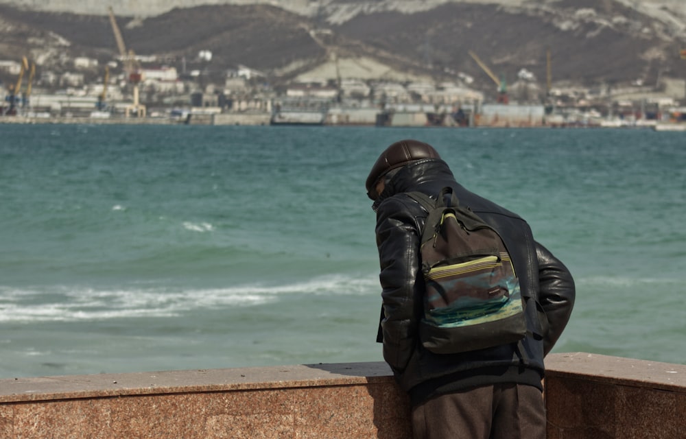 a man with a backpack looking out over the water