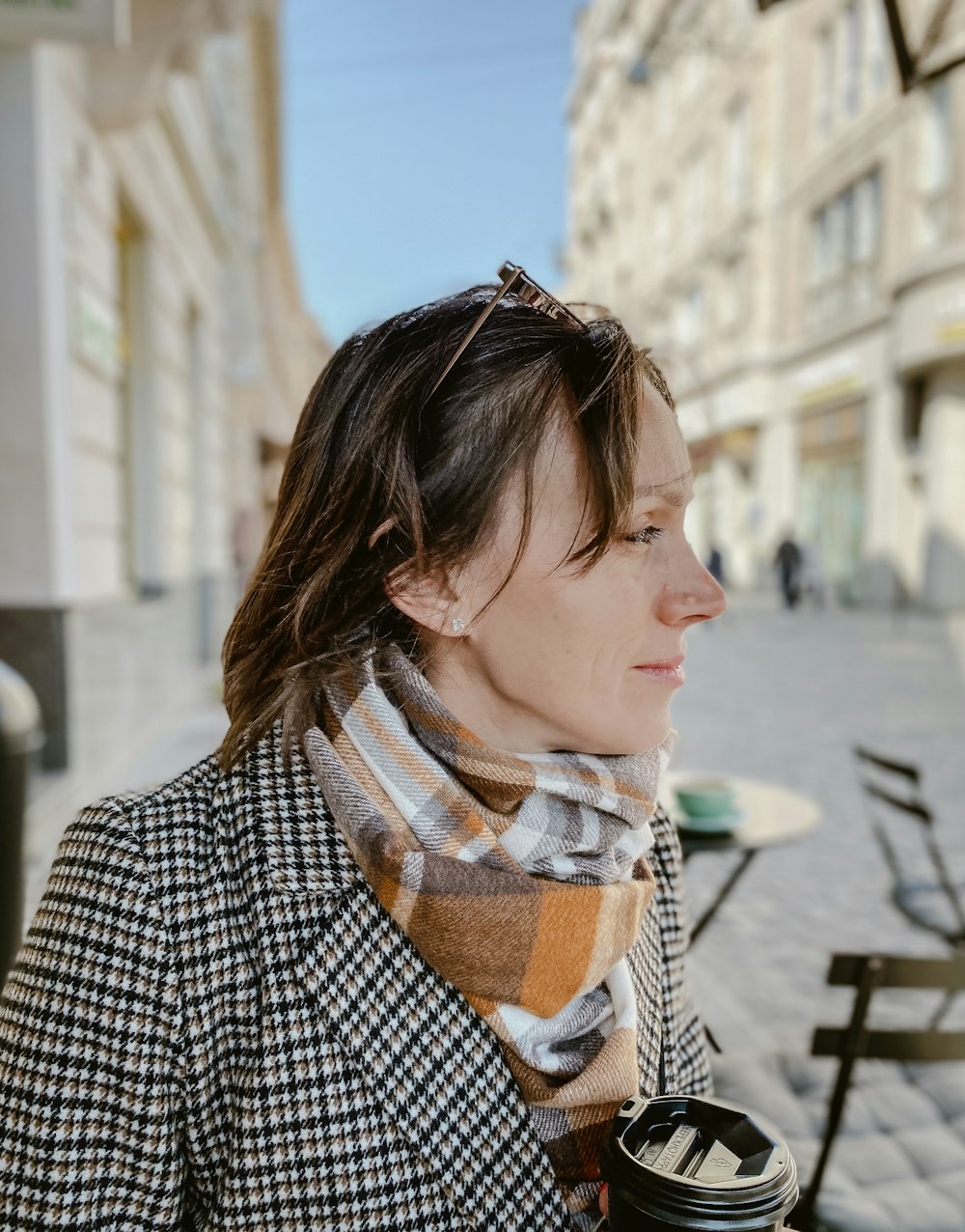 a woman with a plaid coat and a plaid scarf holding a coffee cup