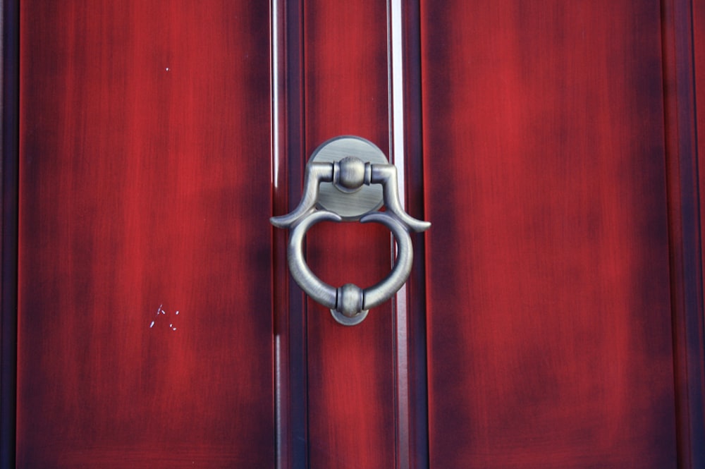 a close up of a metal handle on a red door