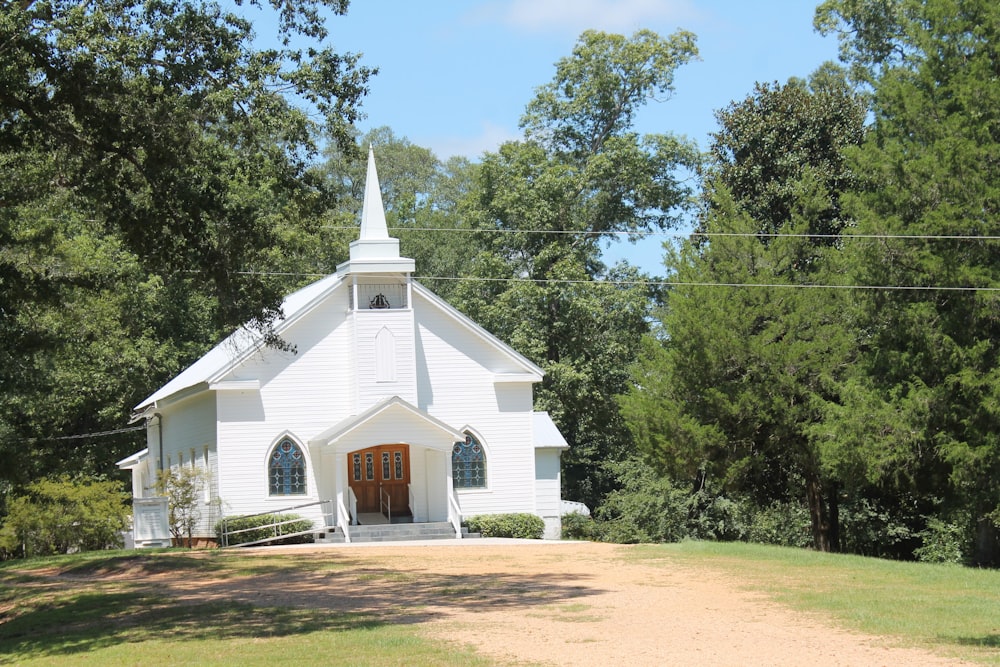 a white church with a steeple surrounded by trees