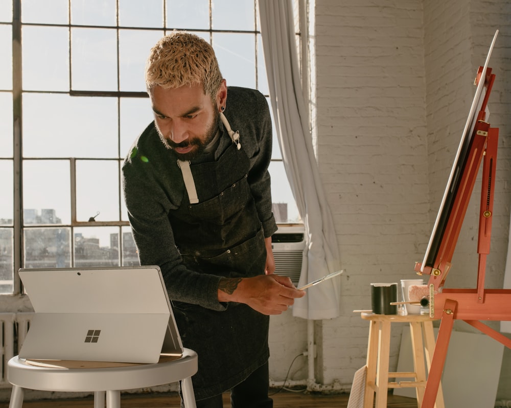 a man is painting a picture on a laptop