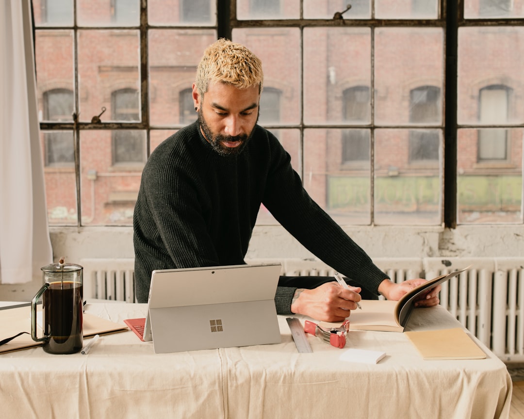 a man sitting at a table working on a laptop,