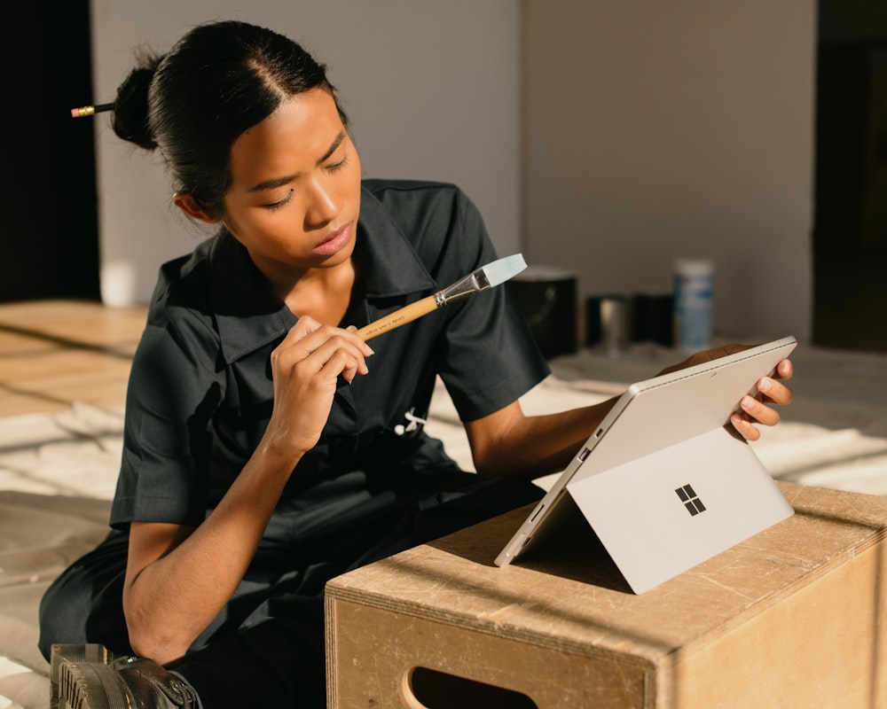 a woman sitting on a box holding a paintbrush