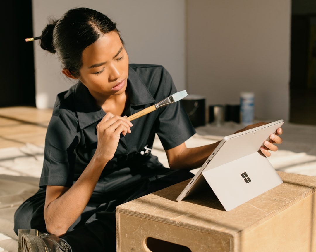 a woman sitting on a box holding a paintbrush,