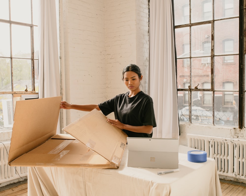 a woman standing next to a cardboard box on top of a table