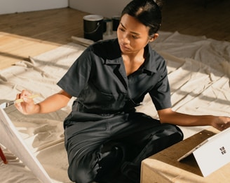 a woman sitting on the floor painting a picture