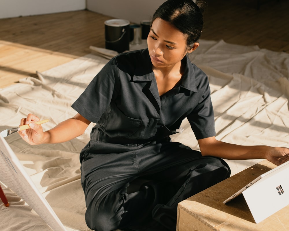 a woman sitting on the floor painting a picture