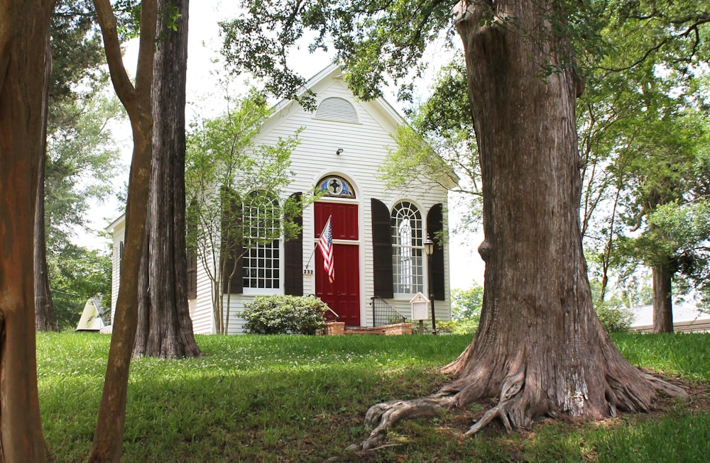 a white house with a red door surrounded by trees