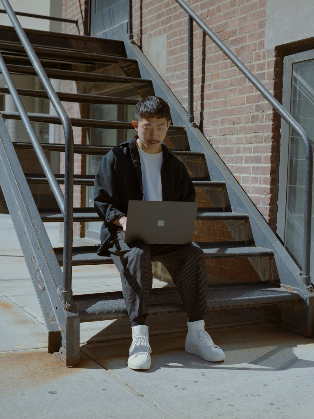 a man sitting on a set of stairs using a laptop