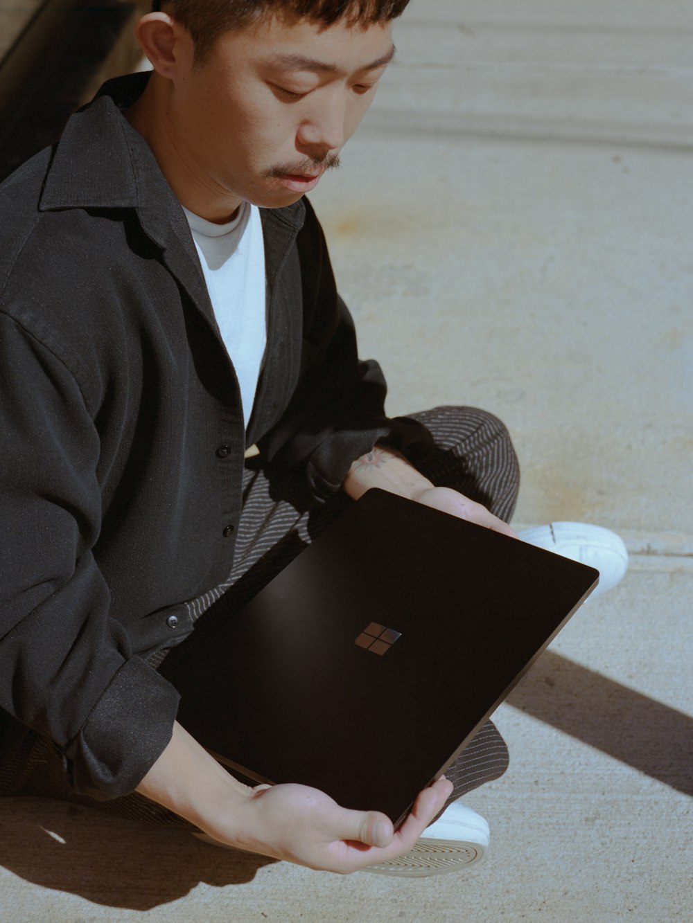 a man sitting on the ground holding a laptop