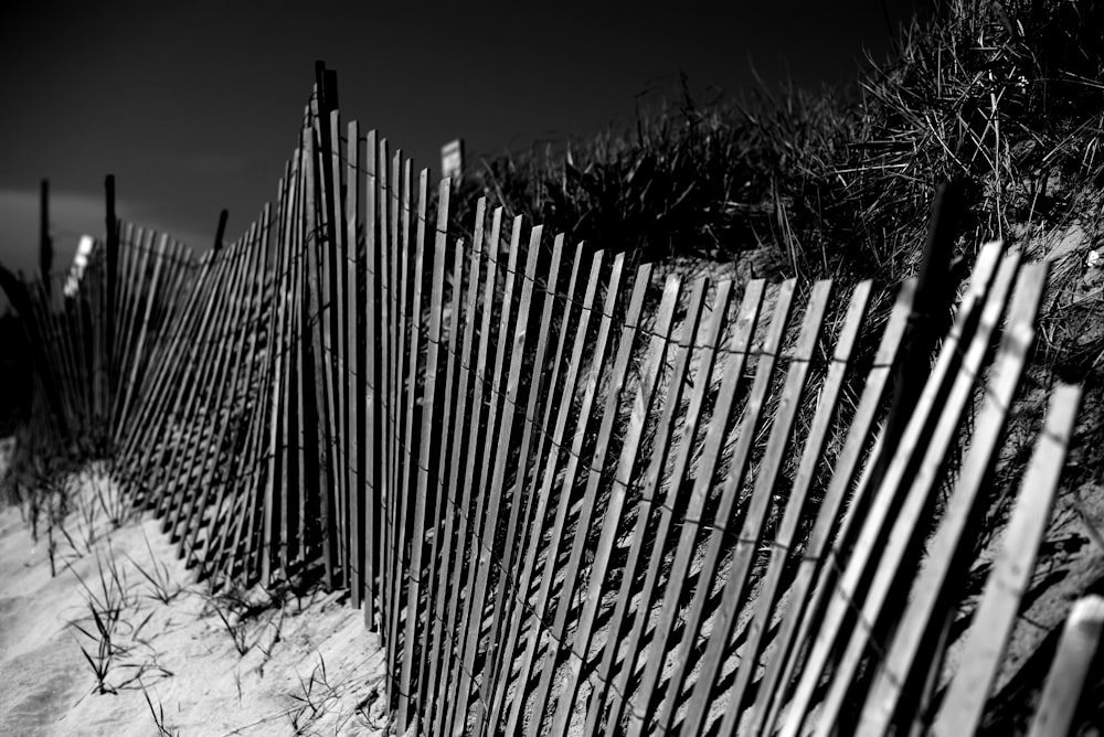 a black and white photo of a beach fence