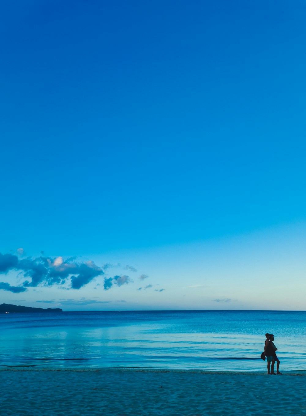 a person standing on a beach flying a kite