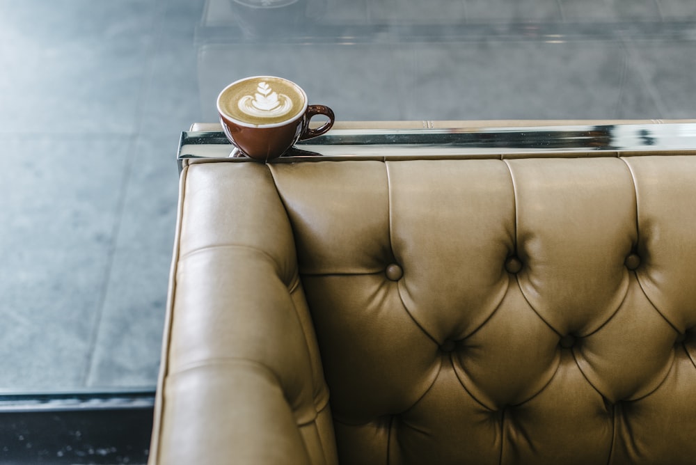茶色のソファの上に座っている一杯のコーヒー