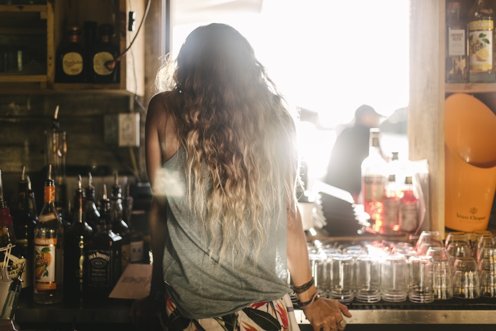 a woman standing in front of a bar filled with bottles