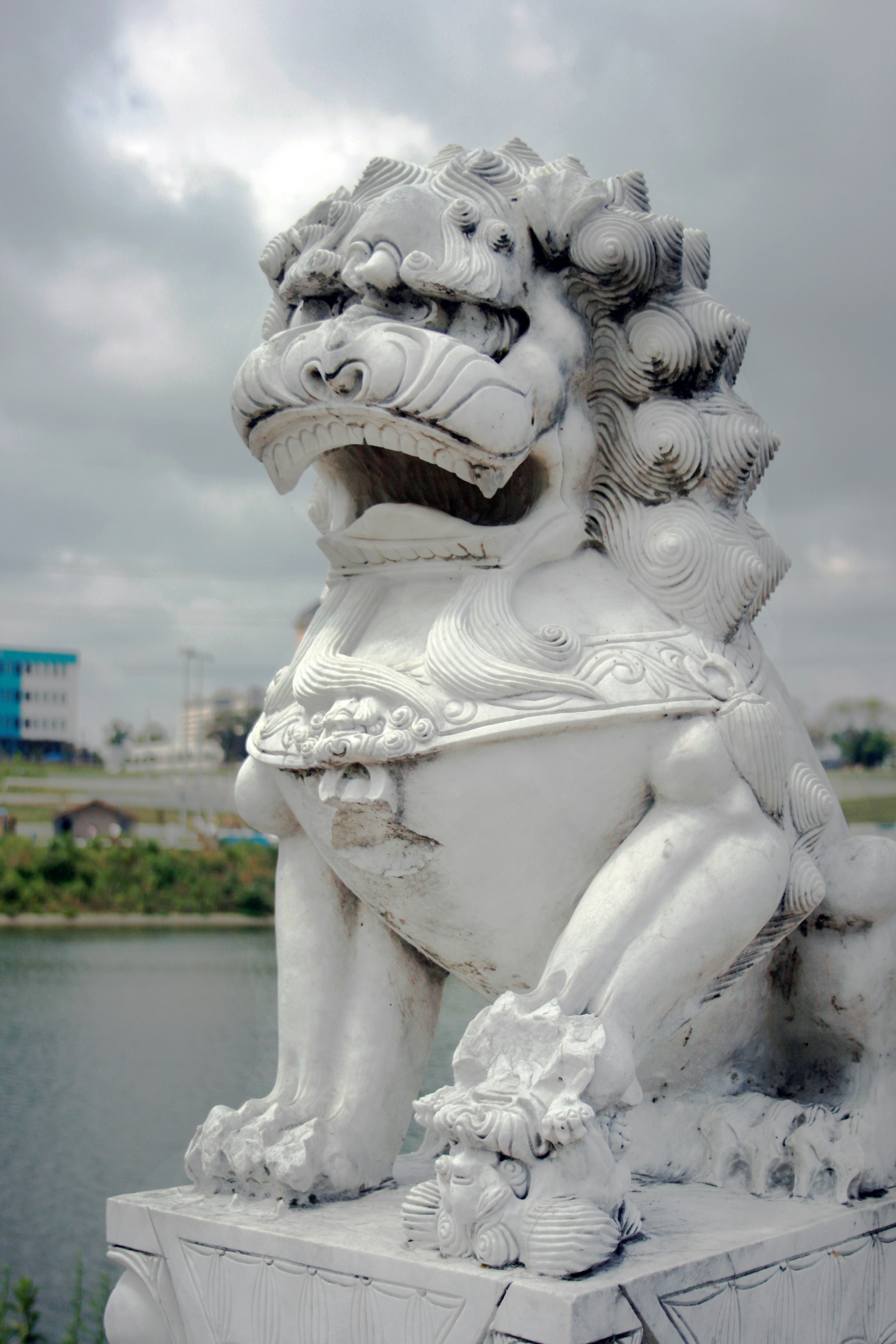 une statue d’un lion assis au sommet d’un bloc de ciment