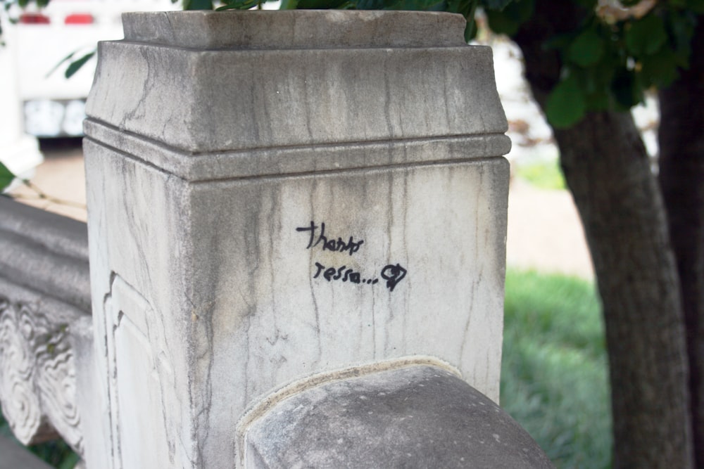 a cement pillar with writing on it next to a tree