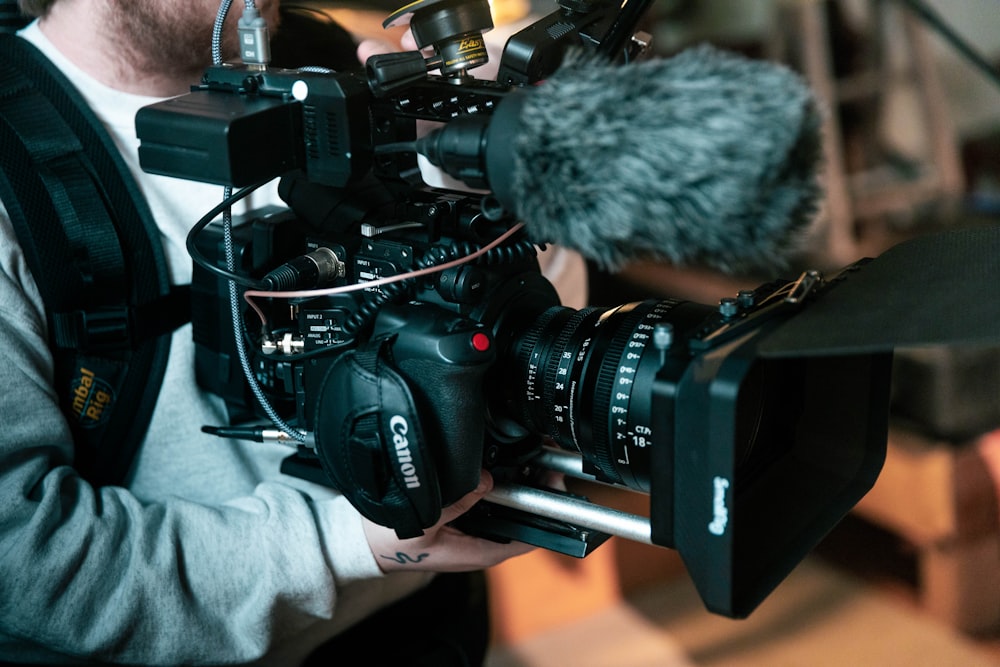 a man holding a camera with a microphone attached to it