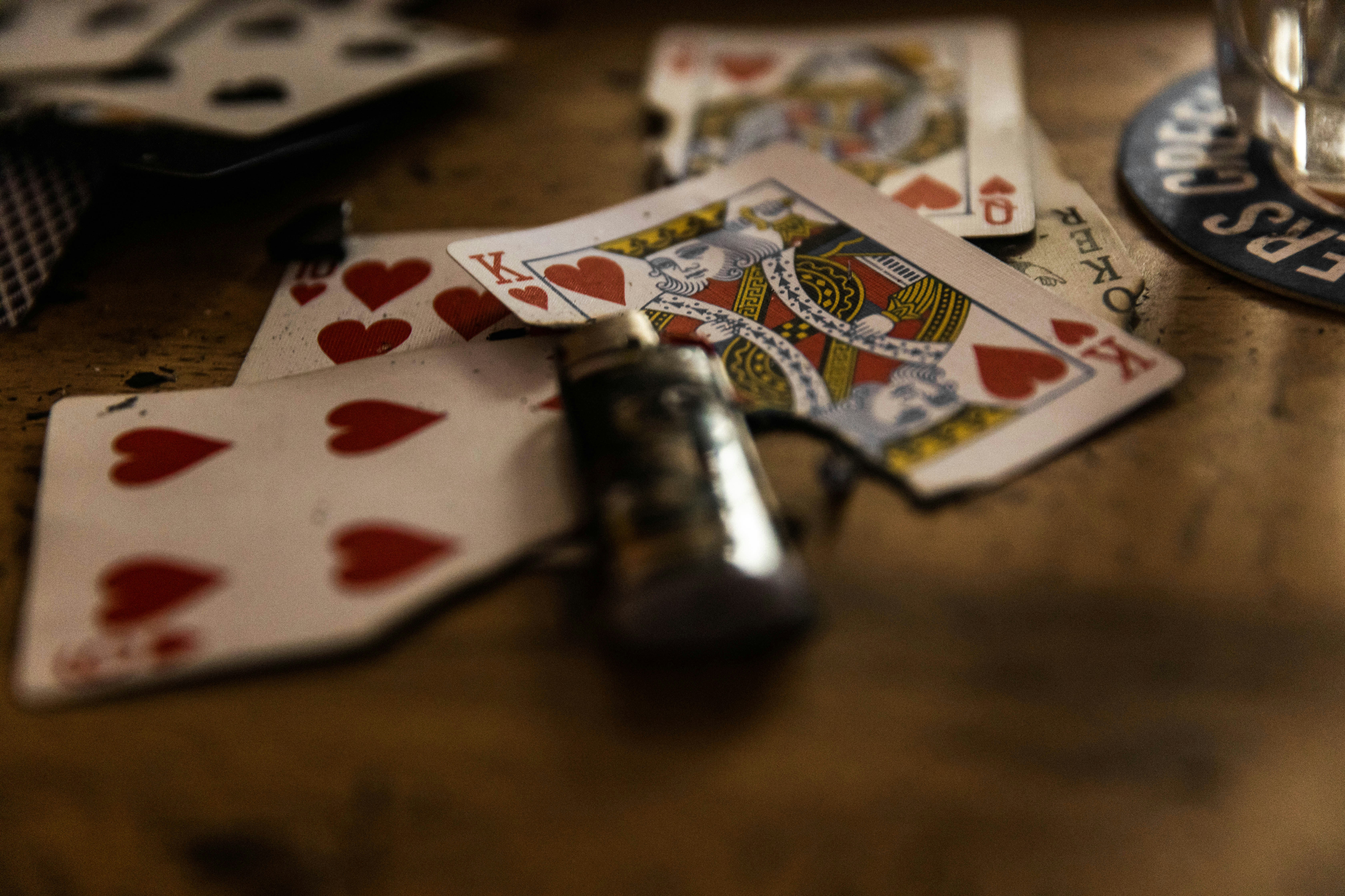 a wooden table topped with playing cards and a glass of water