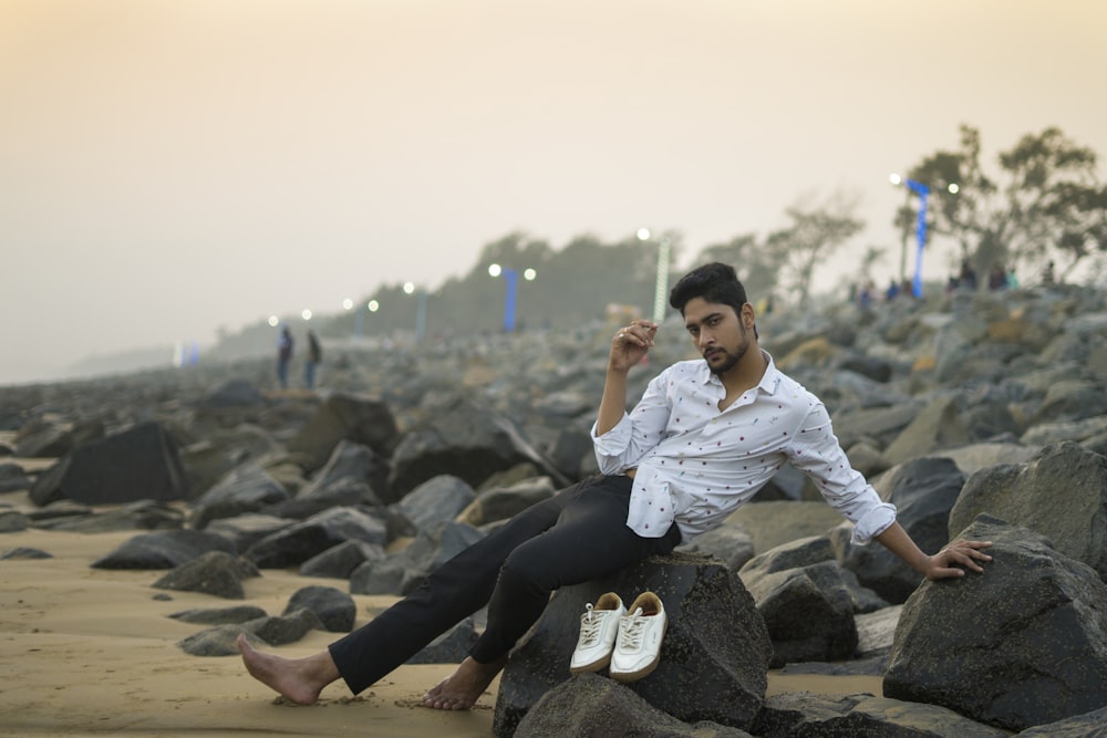 a man sitting on a rock on the beach