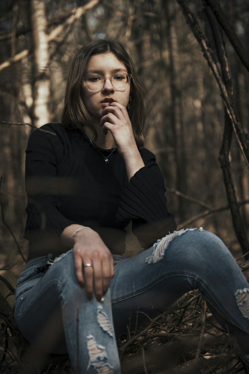 a woman sitting on the ground in the woods