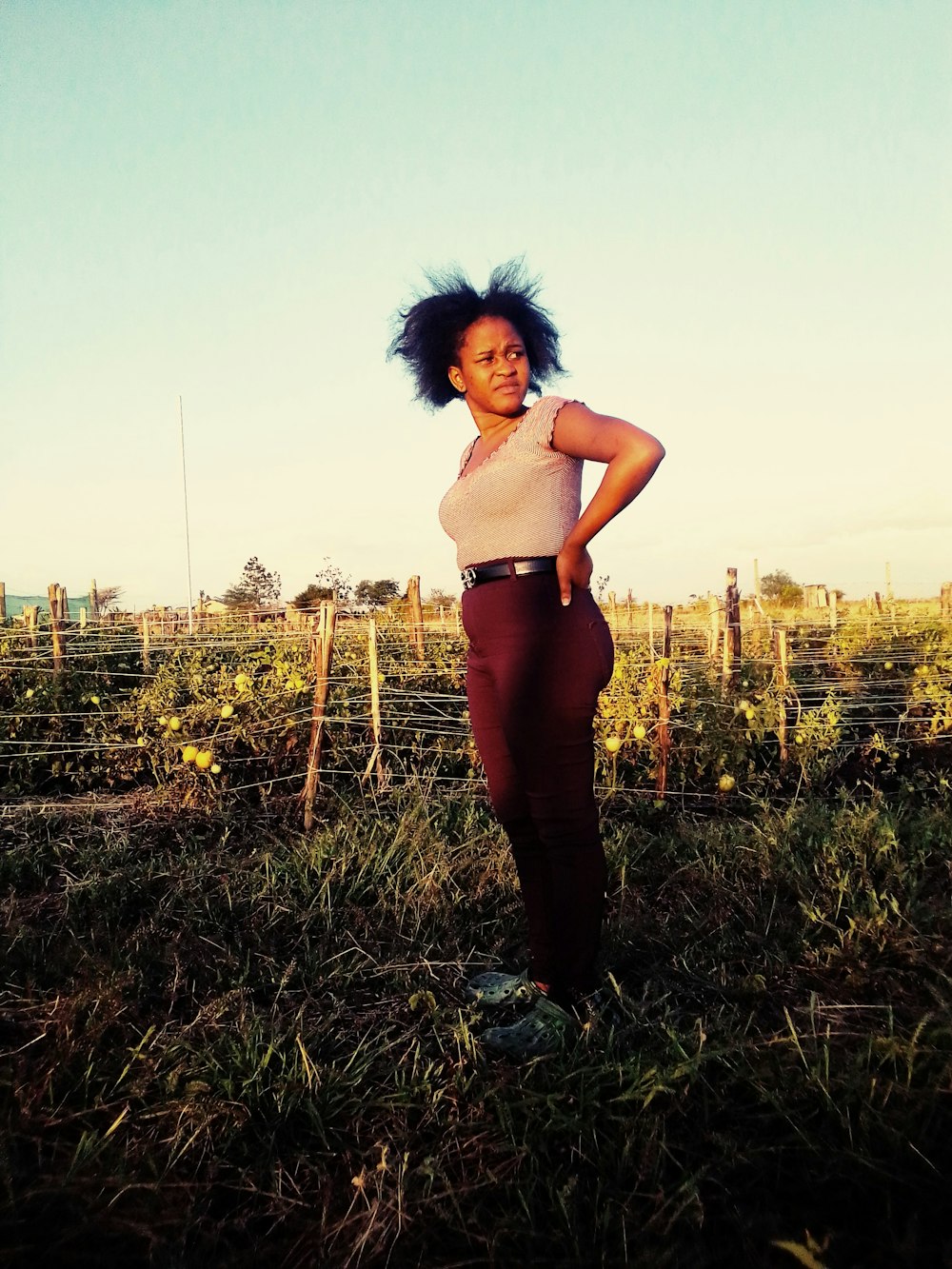 a woman standing in a field with her hair blowing in the wind