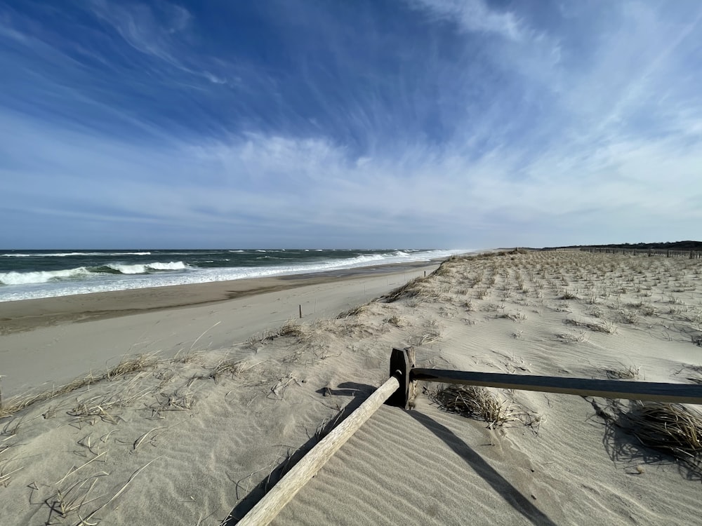 uma vista de uma praia com uma cerca em primeiro plano