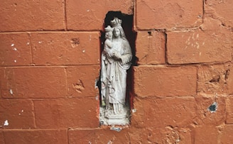 a statue of a virgin mary on a brick wall