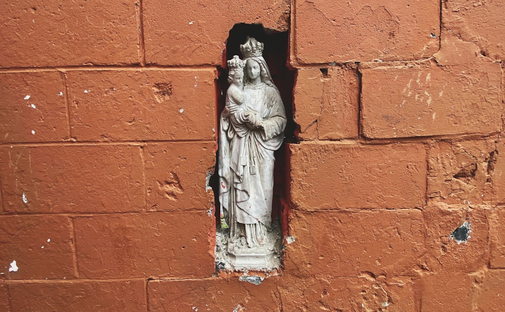 Una estatua de una Virgen María en una pared de ladrillo